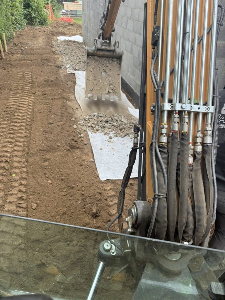 Pose d’un système de drainage le long d’un bâtiment avec tranchée, géotextile et couche de graviers